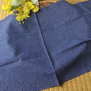 May include: A blue fabric with a white polka dot pattern. The fabric is folded in half and has a slight wrinkle.