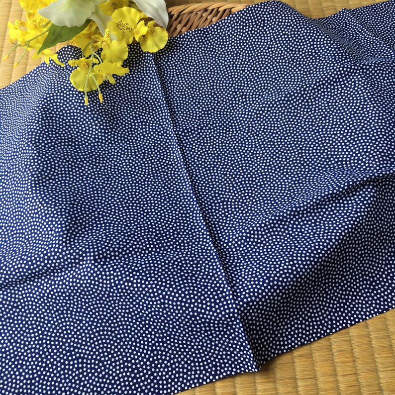 May include: A blue fabric with a white polka dot pattern. The fabric is folded in half and has a slight wrinkle.