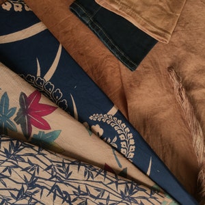 May include: A close-up of a fabric with a blue and white floral pattern. The fabric is layered on top of a brown fabric with a textured surface.