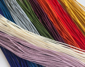 May include: A collection of colorful cords in various shades of blue, purple, white, green, brown, orange, red, and yellow. The cords are arranged in a fan shape, with the darkest colors at the bottom and the lightest colors at the top.