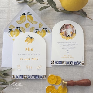 May include: A baby announcement set featuring a lemon theme. The set includes cards with text, an envelope with lemon illustrations, and yellow wax seals. The cards have a blue and white border and the text "Mio" and "27 août 2025".