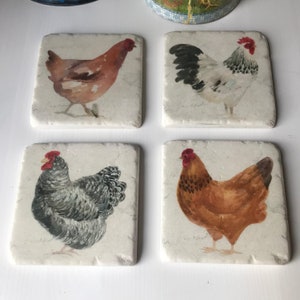 May include: Set of four square ceramic coasters featuring watercolour illustrations of chickens. Each coaster has a different chicken design, including a brown hen, a white rooster, a grey hen, and a brown hen.