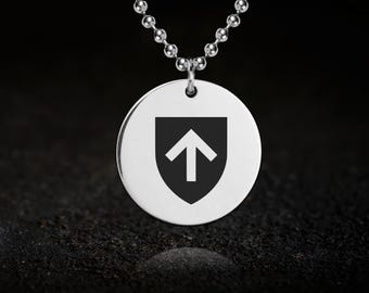 May include: A silver-colored pendant necklace with a round charm. The charm features a black shield shape with a white arrow pointing upwards. The necklace has a ball chain design.