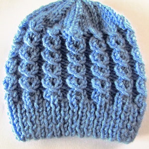 May include: A blue knitted hat with a cable knit pattern.
