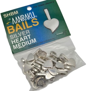 May include: A clear plastic bag filled with silver heart-shaped bails. The bag is partially visible, with a green and blue label that reads "Aanraku Bails Silver Heart Medium" and "For Glass Jewelry."