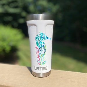 May include: White travel mug with a seahorse design in shades of blue, green, pink, and white. The seahorse has a monogram in the center and the words "LIFE TIME" at the bottom.