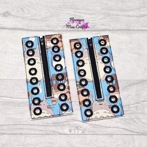 May include: Two fabric zipper pulls with a blue and white pattern featuring a cartoon character. The zipper pulls have black eyelets and a black zipper.