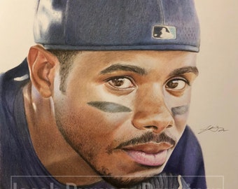 Può includere: Un disegno a matita di un giocatore di baseball che indossa un berretto da baseball blu con un logo bianco. Il giocatore sta guardando in basso e ha un'espressione seria sul viso. Il disegno è firmato "J.B." nell'angolo in basso a destra.