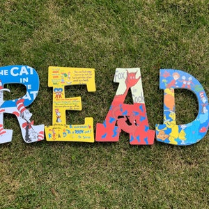 May include: Colorful wooden letters spelling "READ" with illustrations from Dr. Seuss books. The letters are painted in red, blue, yellow, and white.