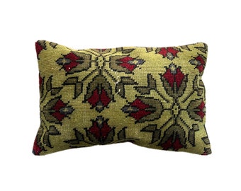 May include: Rectangular decorative pillow with a floral pattern. The pillow features a light green background with a repeating design of red and gray flowers. The pillow is made of a textured fabric.