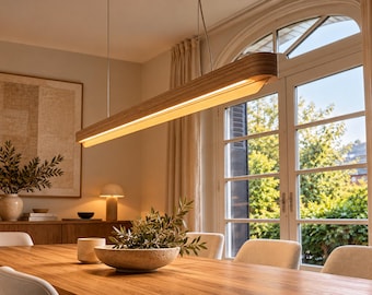 May include: A linear pendant light fixture featuring a long, curved wooden frame with a light-colored wood grain finish. The fixture is suspended by thin wires and contains an integrated LED light strip that emits a warm, downward-facing glow.