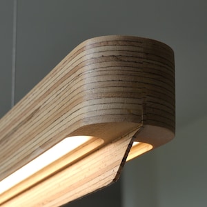 May include: A modern, wooden pendant light fitting with a sleek, curved design. The light is made of natural wood and features a built-in LED strip.