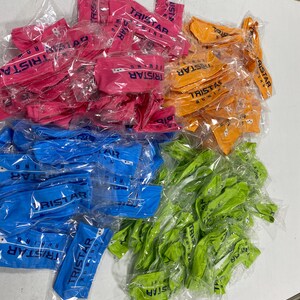 May include: A large pile of colorful headbands with the logo "TRISTAR RUNNING" printed on them. The headbands are packaged individually in clear plastic bags.