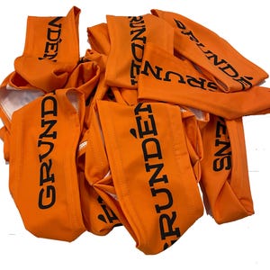 May include: A pile of orange fabric arm bands with the word "GRUNDENS" printed in black.