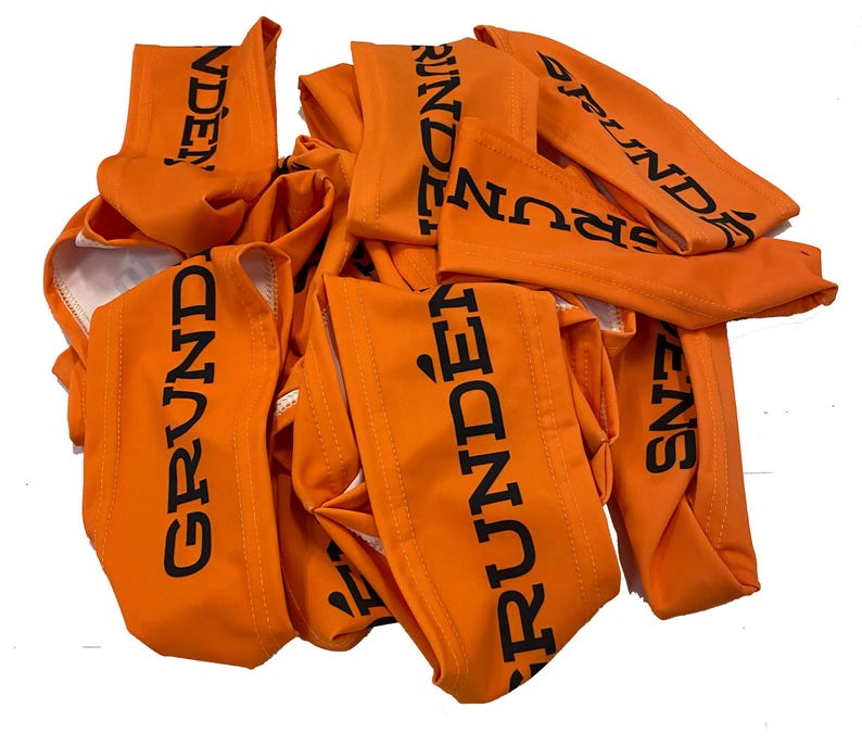 May include: A pile of orange fabric arm bands with the word "GRUNDENS" printed in black.