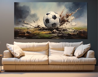 Puede incluir: Una gran impresión en lienzo que representa un balón de fútbol atravesando un paisaje rocoso. El balón es blanco y negro, con un efecto de salpicadura dinámico marrón y blanco. El fondo presenta un cielo nublado y hierba verde.
