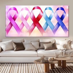 May include: A canvas print featuring five colorful awareness ribbons: purple, pink, red, light blue, and dark blue. The ribbons are arranged in a row against a soft, blurred background. The artwork is displayed above a white sofa with decorative pillows.