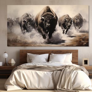 May include: A large rectangular canvas print depicts a herd of bison running through a dusty landscape. The bison are dark brown with prominent horns, and the artwork uses a muted color palette of browns, tans, and whites.