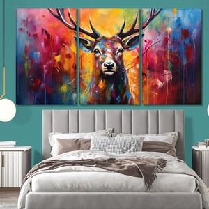 May include: A colourful abstract painting of a deer with large antlers. The deer is painted in shades of red, orange, yellow, green, blue, and purple. The background is a blur of colours.