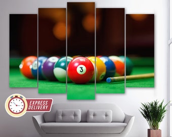 Op de afbeelding: Een meerpaneels canvasprint met een close-up van een set biljartballen op een groene pooltafel. De ballen zijn in een rij gerangschikt, met de bal met nummer "3" in het midden. De achtergrond is wazig, waardoor een gevoel van diepte en beweging ontstaat.