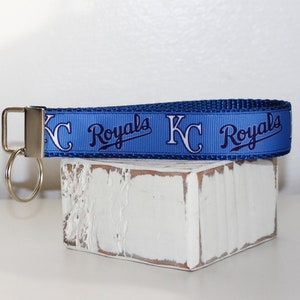 May include: A blue and white key chain with the text "KC Royals" repeated on the strap. The key chain has a silver key ring.