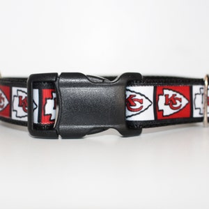 Peut inclure: Un collier de chien noir avec un ruban &agrave; motif rouge, blanc et noir repr&eacute;sentant le logo des Kansas City Chiefs. Le collier a une boucle en plastique noire.