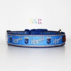 Puede incluir: Collar para perro azul y blanco con el logotipo de los Kansas City Royals repetido. El logotipo presenta las palabras "Royals" en blanco con una corona dorada sobre las palabras "KC".