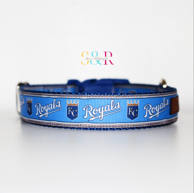 Puede incluir: Collar para perro azul y blanco con el logotipo de los Kansas City Royals repetido. El logotipo presenta las palabras "Royals" en blanco con una corona dorada sobre las palabras "KC".