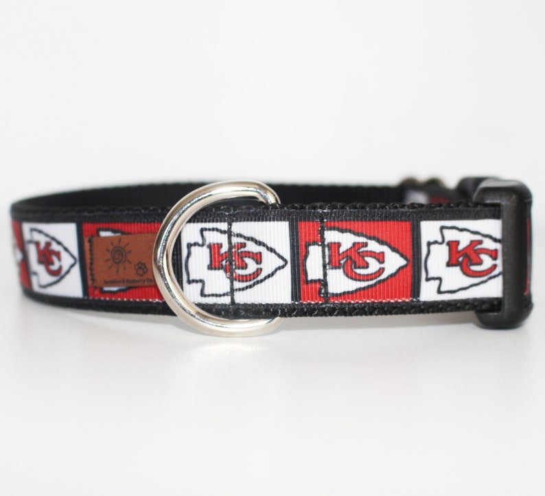 Peut inclure: Un collier de chien noir avec un motif rouge, blanc et noir repr&eacute;sentant le logo des Kansas City Chiefs. Le collier a un anneau en D en m&eacute;tal argent&eacute;.