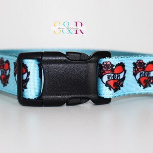 May include: A light blue dog collar with a black buckle. The collar has a repeating pattern of red hearts with black outlines and the word "MOM" inside each heart. The hearts are surrounded by black roses.