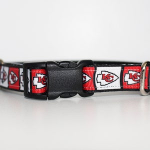 Peut inclure: Un collier de chien rouge, blanc et noir avec un motif r&eacute;p&eacute;t&eacute; du logo des Chiefs de Kansas City. Le collier a une boucle en plastique noire.