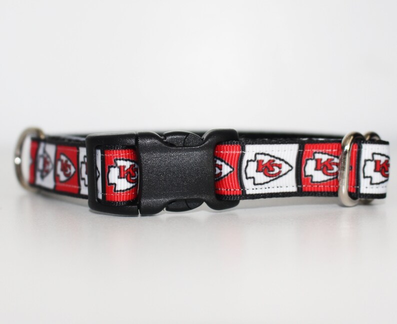 Peut inclure: Un collier de chien rouge, blanc et noir avec un motif r&eacute;p&eacute;t&eacute; du logo des Chiefs de Kansas City. Le collier a une boucle en plastique noire.