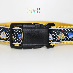 May include: A yellow dog collar with a black buckle and a black and white patterned ribbon featuring colorful moths. The ribbon has white polka dots.