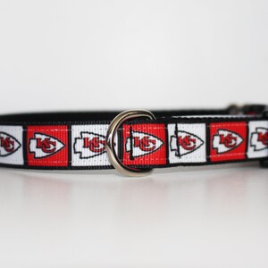 Peut inclure: Un collier de chien noir avec un ruban &agrave; motif rouge, blanc et noir repr&eacute;sentant le logo des Kansas City Chiefs.
