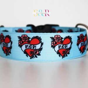 May include: Light blue dog collar with a repeating pattern of red hearts with black outlines and the word "MOM" in a banner. The hearts are surrounded by black floral designs.