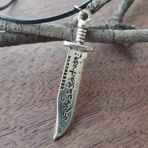 May include: Silver sword pendant necklace with a black cord. The sword has Japanese text engraved on it.