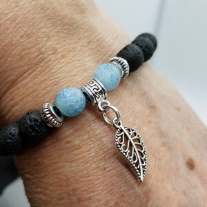 Peut inclure: Un bracelet en pierre de lave noire avec des perles d'agate bleues et un pendentif en forme de feuille argentée.