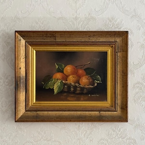 Peut inclure: Peinture à l'huile d'un panier d'oranges avec des feuilles vertes. Les oranges sont d'une couleur orange vif et le panier est tissé. La peinture est dans un cadre doré et le fond est brun foncé.