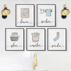 May include: Five black framed prints with white backgrounds and illustrations of laundry tasks. The prints read "laver", "secher", "plier", "repetér", and "perdu".