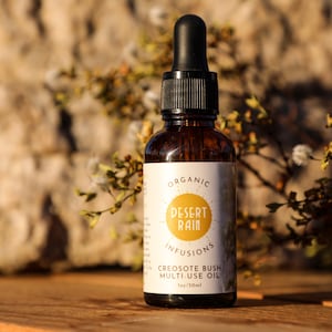 May include: A brown glass bottle with a dropper top, labeled "Organic Desert Rain Infusions Creosote Bush Multi-Use Oil 1oz/30ml".