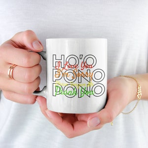 May include: White ceramic mug with black outline and colorful text that reads "HO'O I Love You,  I'm Sorry,  Please Forgive Me,  Thank You".