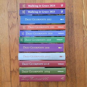 May include: A stack of 12 books with red, blue, green, and purple covers. The books are titled "Daily Guideposts" and "Walking in Grace" with the years 2014 through 2024.