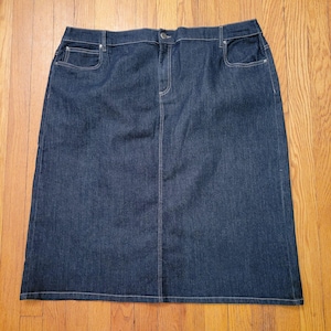 Può includere: Una gonna di jeans blu scuro con taglio dritto e chiusura con bottone e cerniera.