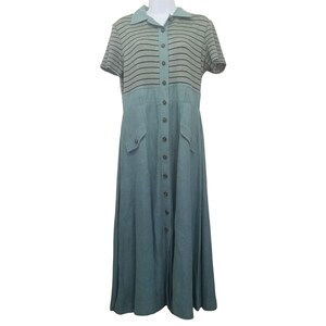 Puede incluir: Un vestido largo con botones en color verde azulado apagado. La parte superior presenta mangas cortas y una tela gris con rayas negras horizontales. El vestido tiene cuello y dos bolsillos delanteros.