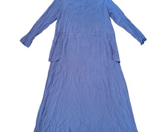 May include: A long-sleeved, periwinkle-colored dress with a round neckline and two front pockets. The dress is made of a soft, flowing fabric and features the brand name "FLAX" on a small tag near the neckline. The dress has a relaxed fit.