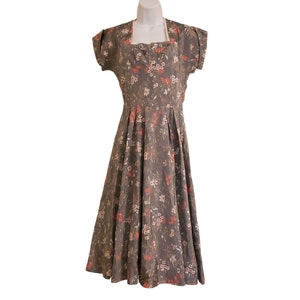 May include: A vintage floral print dress with a square neckline and short sleeves. The dress is a dark gray color with a red and white floral pattern. The dress has a full skirt and is made of a lightweight fabric.