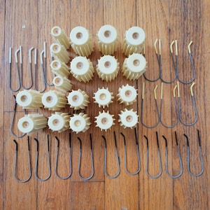 Op de afbeelding: Een set van 20 beige haarrollers met een set van 15 metalen clips. De rollers zijn gerangschikt in een rasterpatroon op een houten oppervlak.
