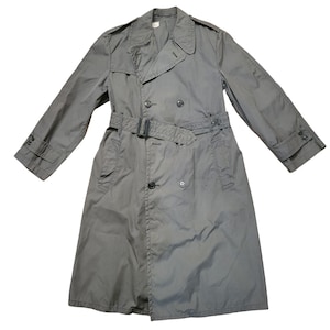 May include: A gray trench coat with a double-breasted design, a belt, and buttoned cuffs. The coat has a classic collar and epaulettes on the shoulders. The coat is made of a lightweight material.