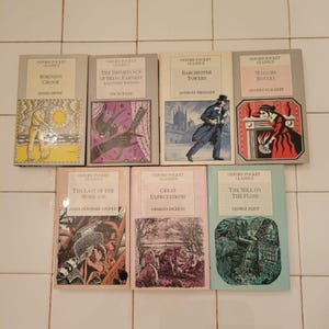 May include: A collection of ten Oxford Pocket Classics paperback books. The books are arranged in two rows of five. The titles include "Robinson Crusoe", "The Importance of Being Earnest", "Barchester Towers", "Madame Bovary", "The Last of the Mohicans", "Great Expectations", and "The Mill on the Floss".