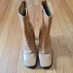 May include: A pair of brown leather boots with a square toe and a zipper on the side.